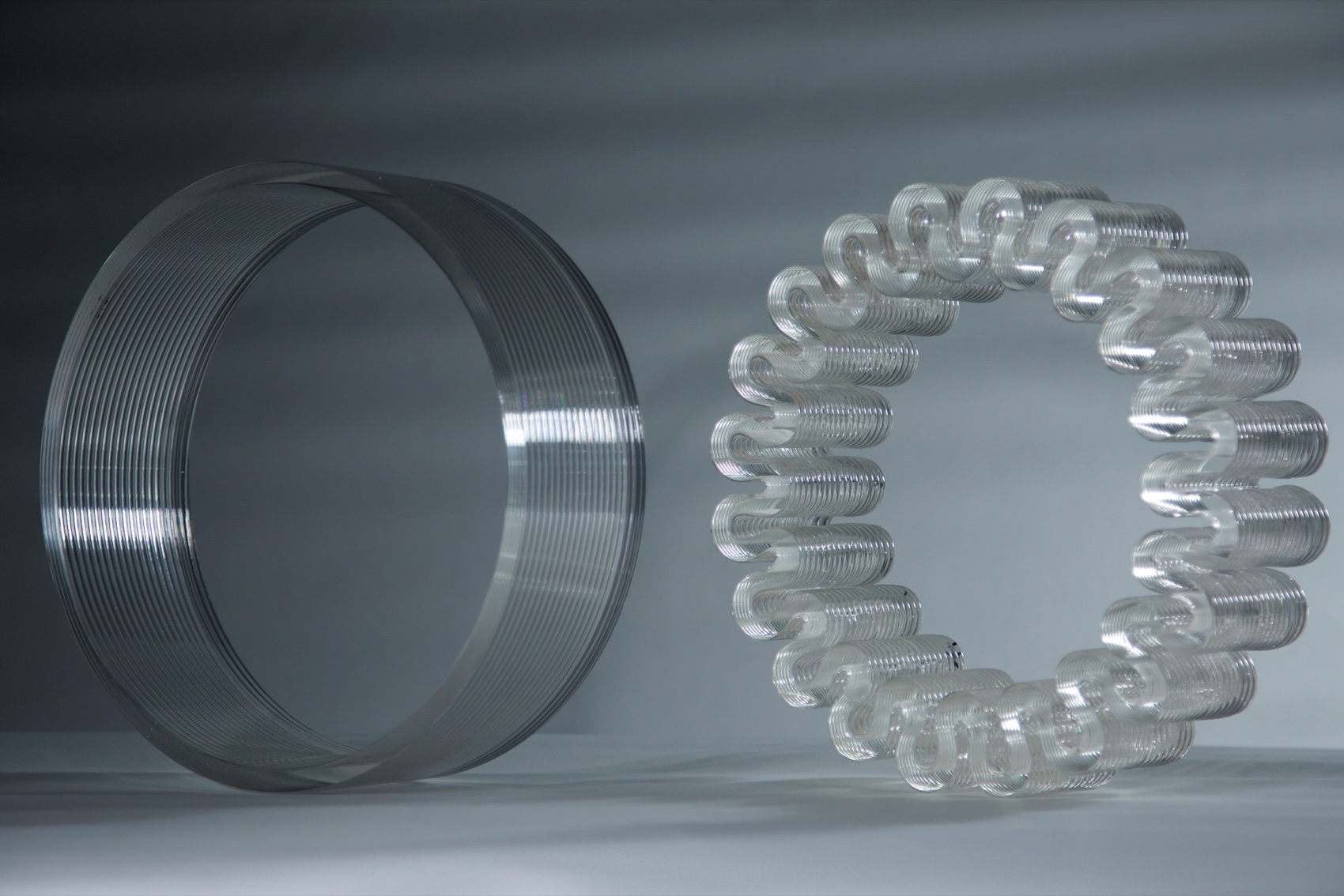 A straight-walled printed glass cylinder beside a coiled ring